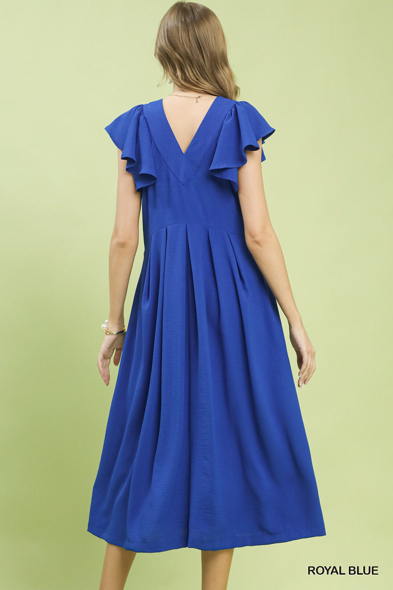 Woman wearing a blue dress with ruffled sleeves on a light green background