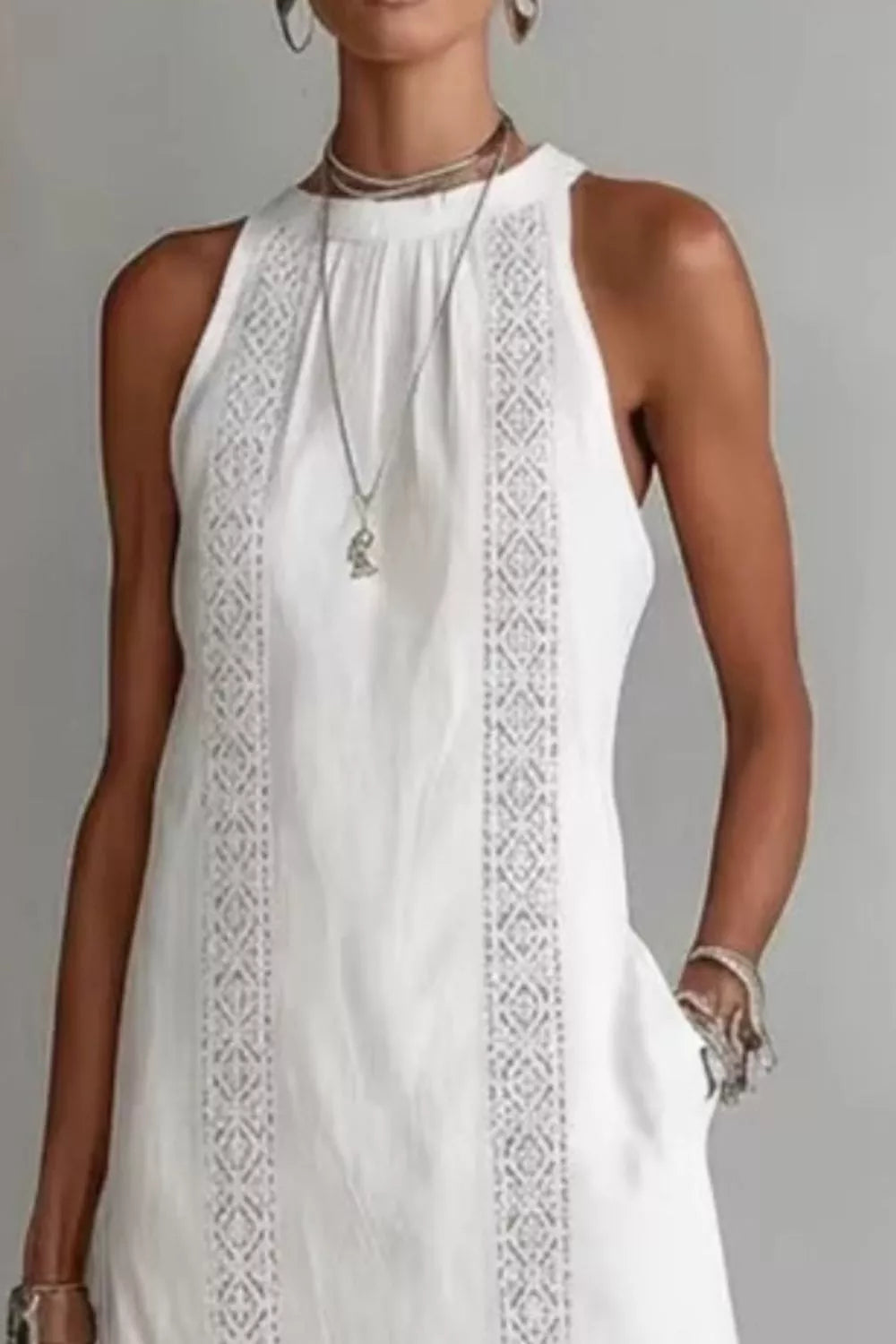 White sleeveless dress with intricate detailing on a plain background