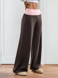 Brown wide-leg pants with a pink waistband worn by a person indoors.