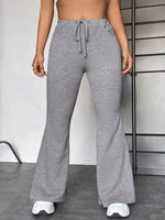 Person wearing gray wide-leg pants with a plain background