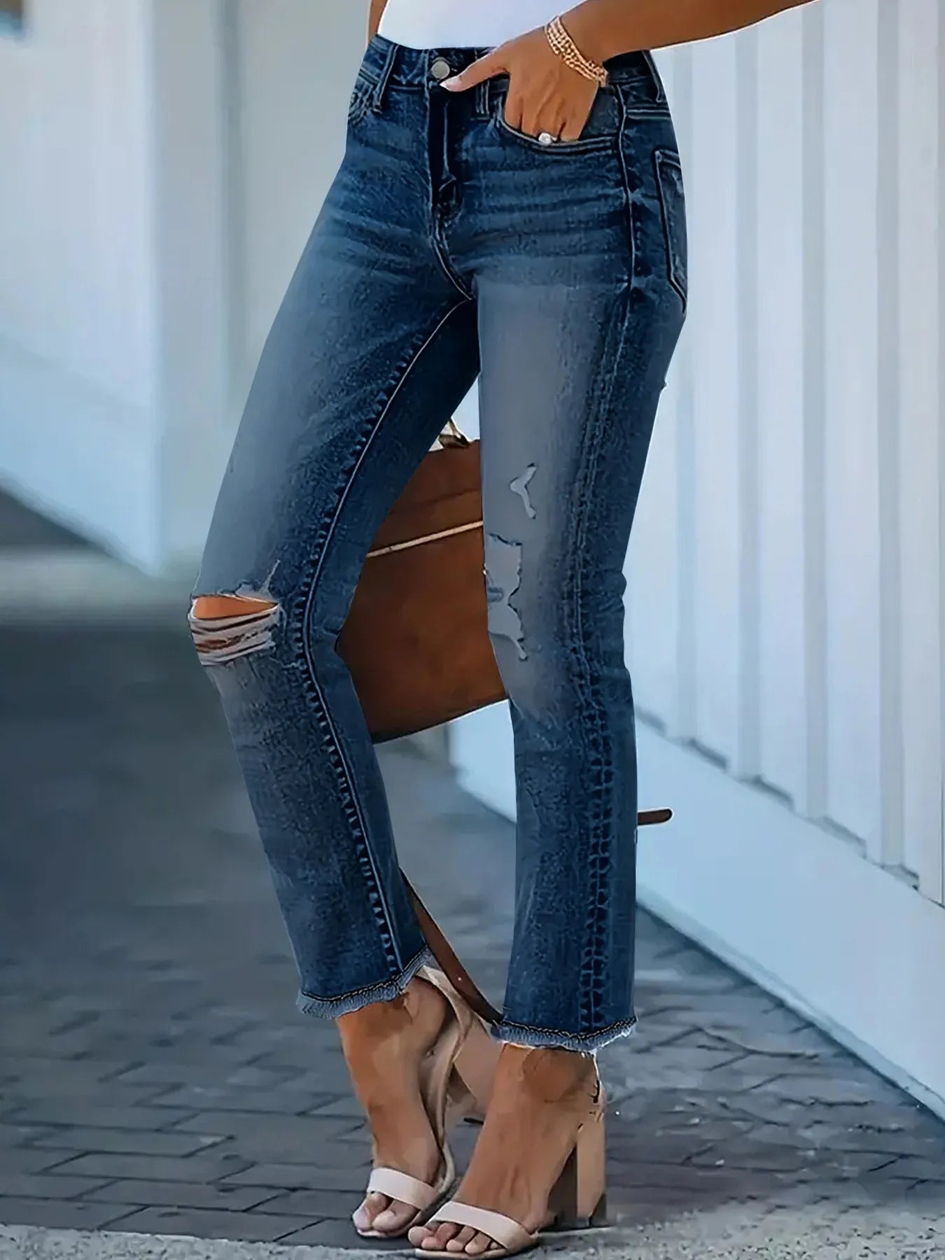 Person wearing blue jeans with a brown handbag on a blurred background