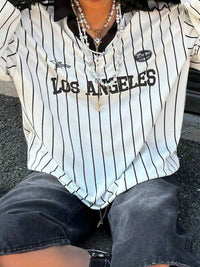 Person wearing a Los Angeles-themed striped shirt sitting on the ground.