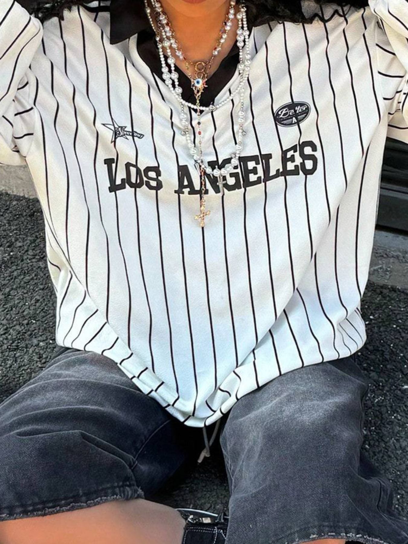 Person wearing a Los Angeles-themed striped shirt sitting on the ground.