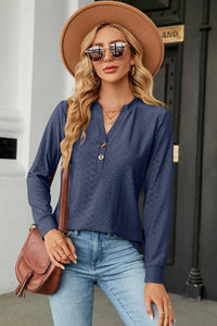 Woman wearing a blue top, jeans, and a brown hat with sunglasses outdoors.