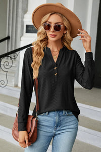 Woman wearing a black long-sleeve top, blue jeans, and a brown hat, holding a brown bag.