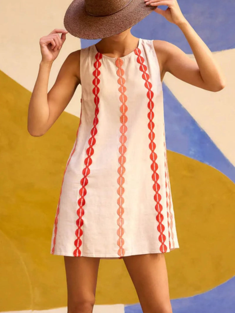 Woman wearing a sleeveless dress with red patterns against a colorful abstract background