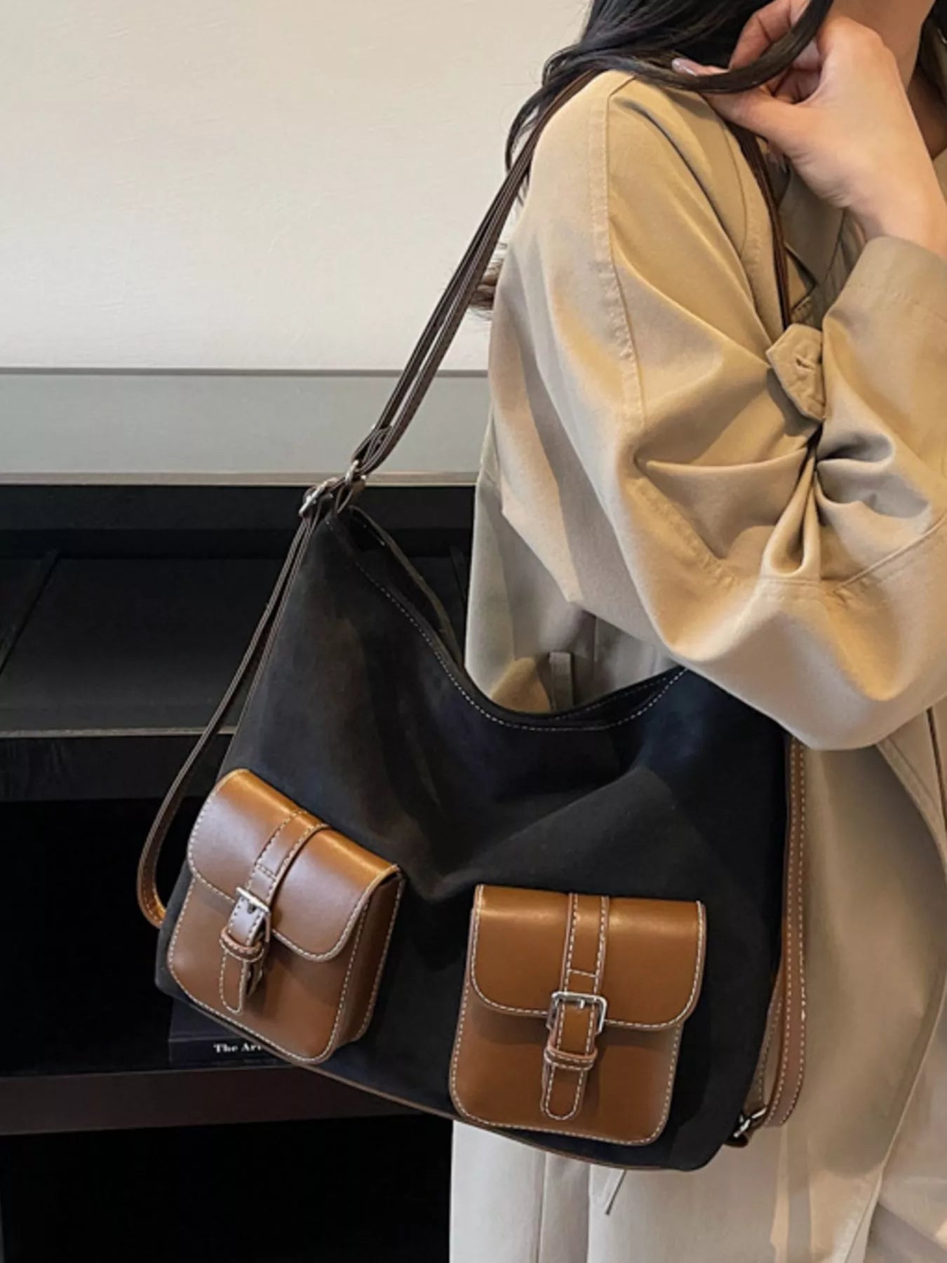 Person holding a black handbag with brown accents