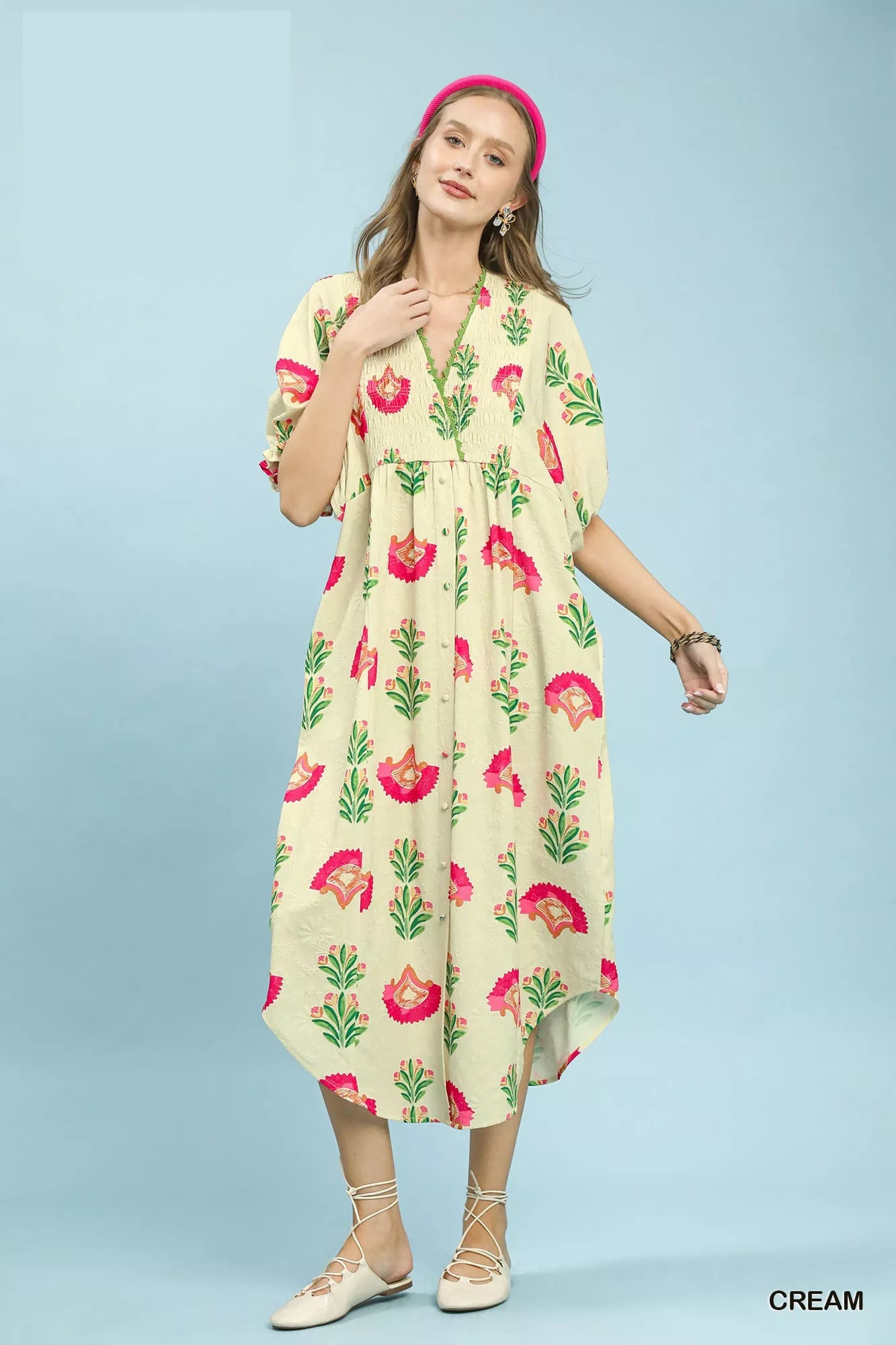 Woman wearing a cream-colored dress with floral pattern on a light blue background