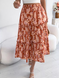 Person wearing a rust-colored floral skirt in a minimal indoor setting.