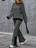 Person wearing a gray sweater and pants with black accents against a gray wall.