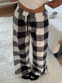 Person wearing black and white checkered pants on a soft surface