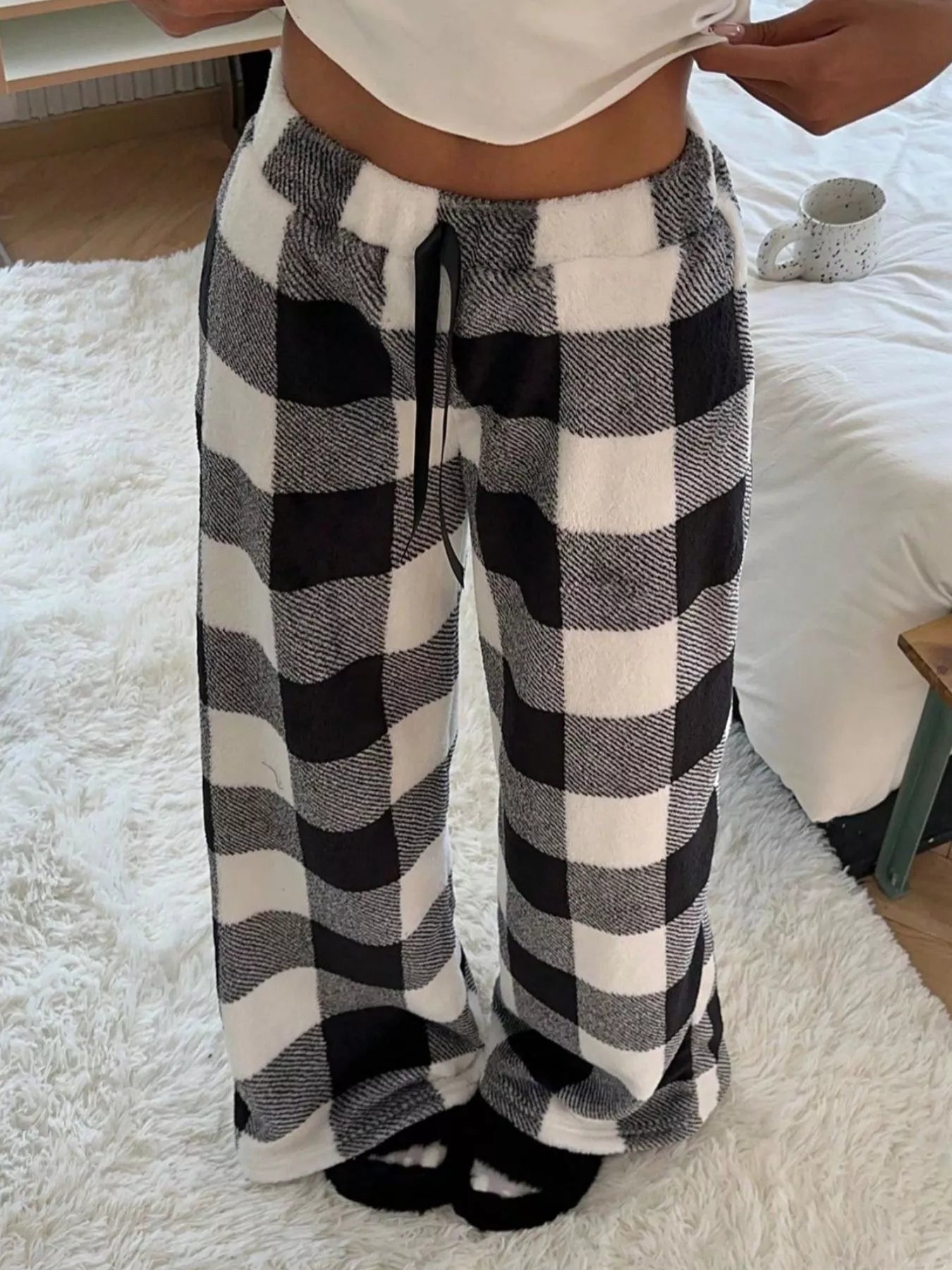 Person wearing black and white checkered pants on a soft surface