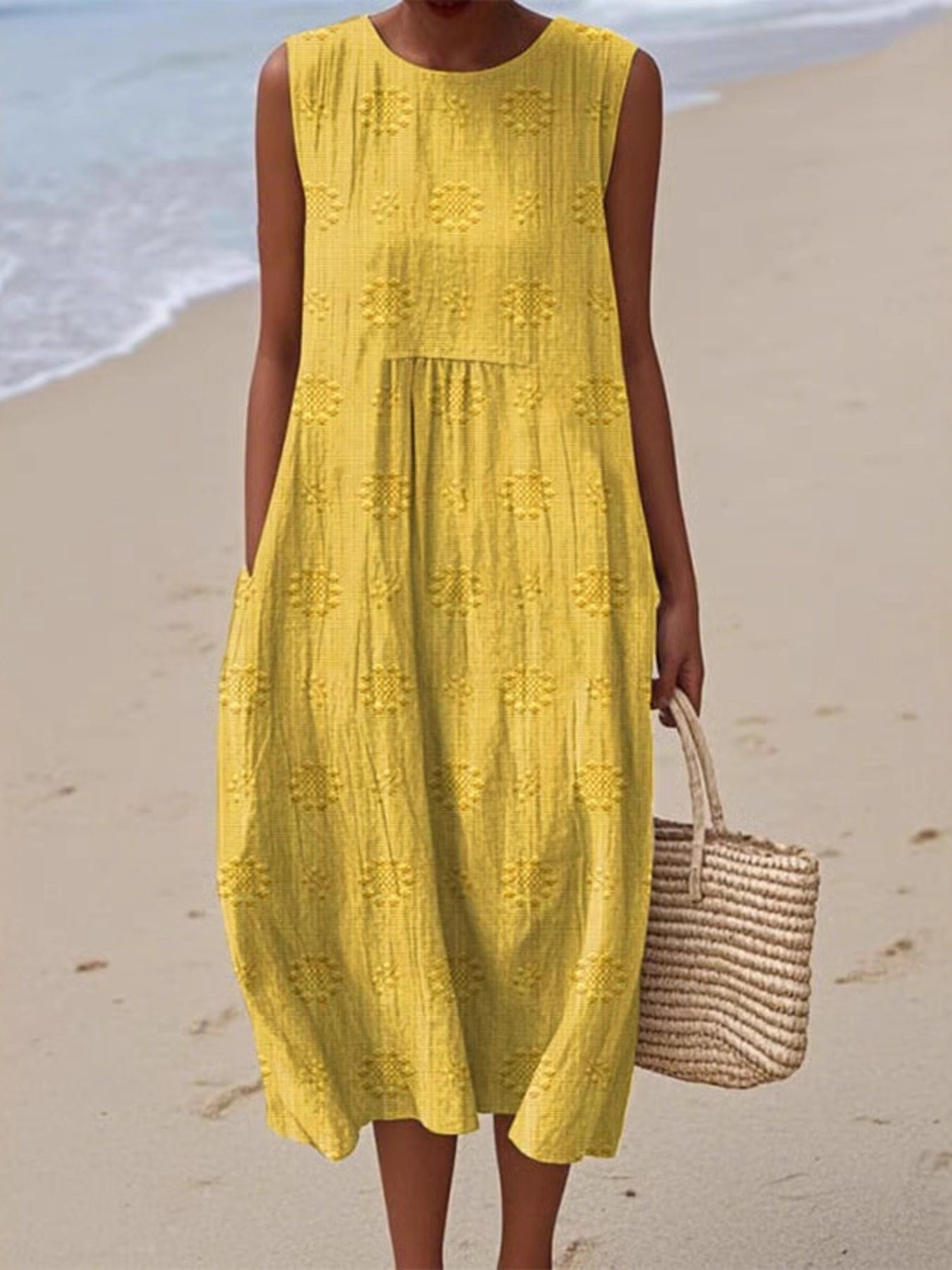 Woman in a yellow dress standing on a beach with ocean in the background