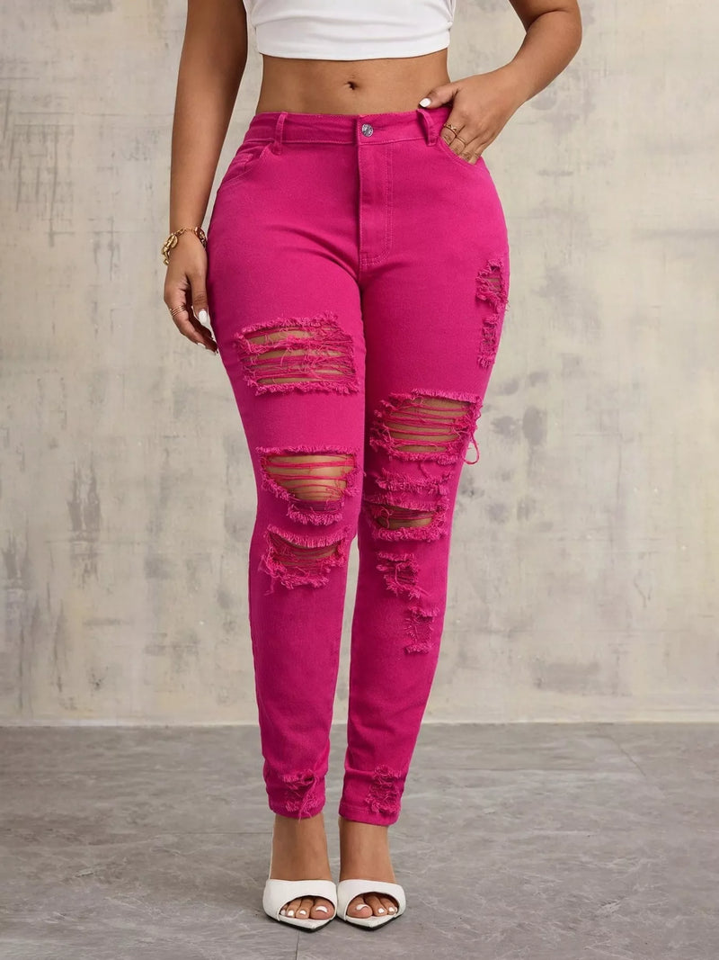 Person wearing bright pink ripped jeans against a plain background