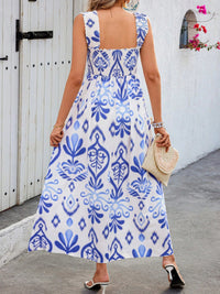 Woman wearing a blue and white patterned dress against a white wall.