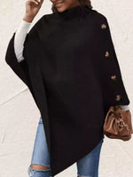 Person wearing a black poncho with gold buttons on a light background