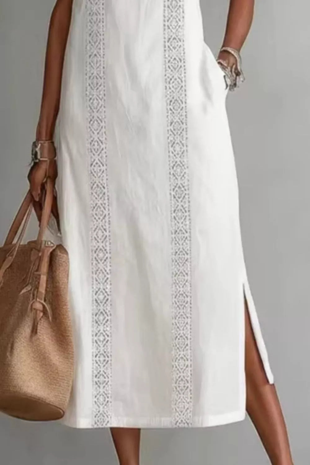 White dress with lace details and a brown handbag on a gray background