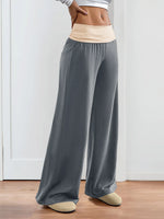 Person wearing gray wide-leg pants with a plain background
