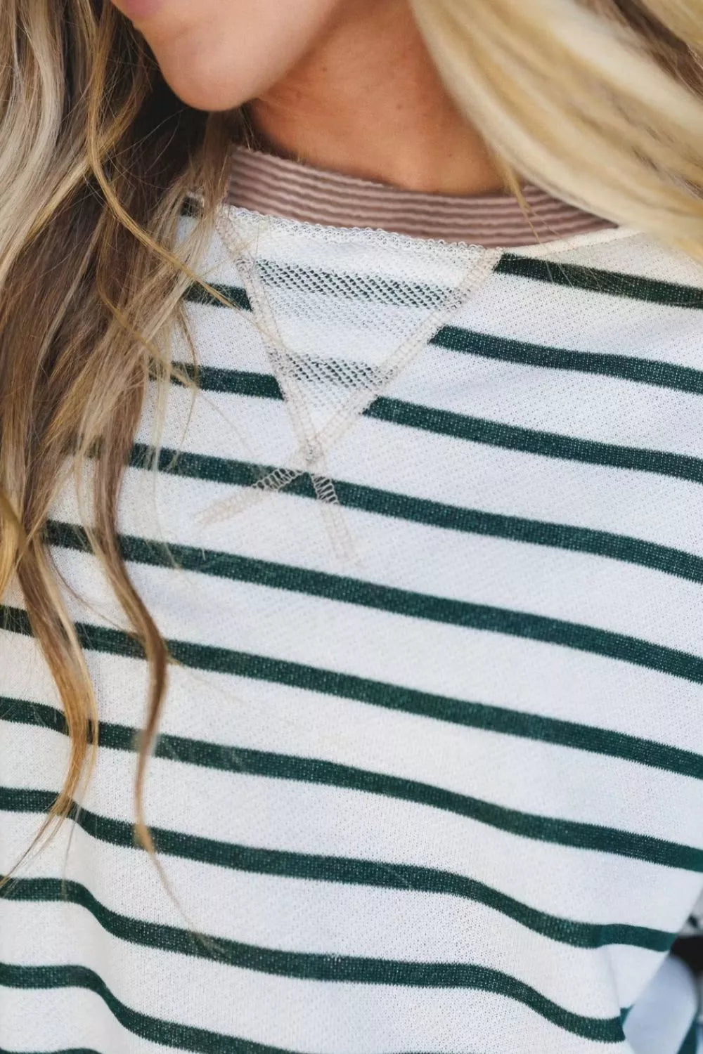 Close-up of a person wearing a green and white striped shirt with a necklace.