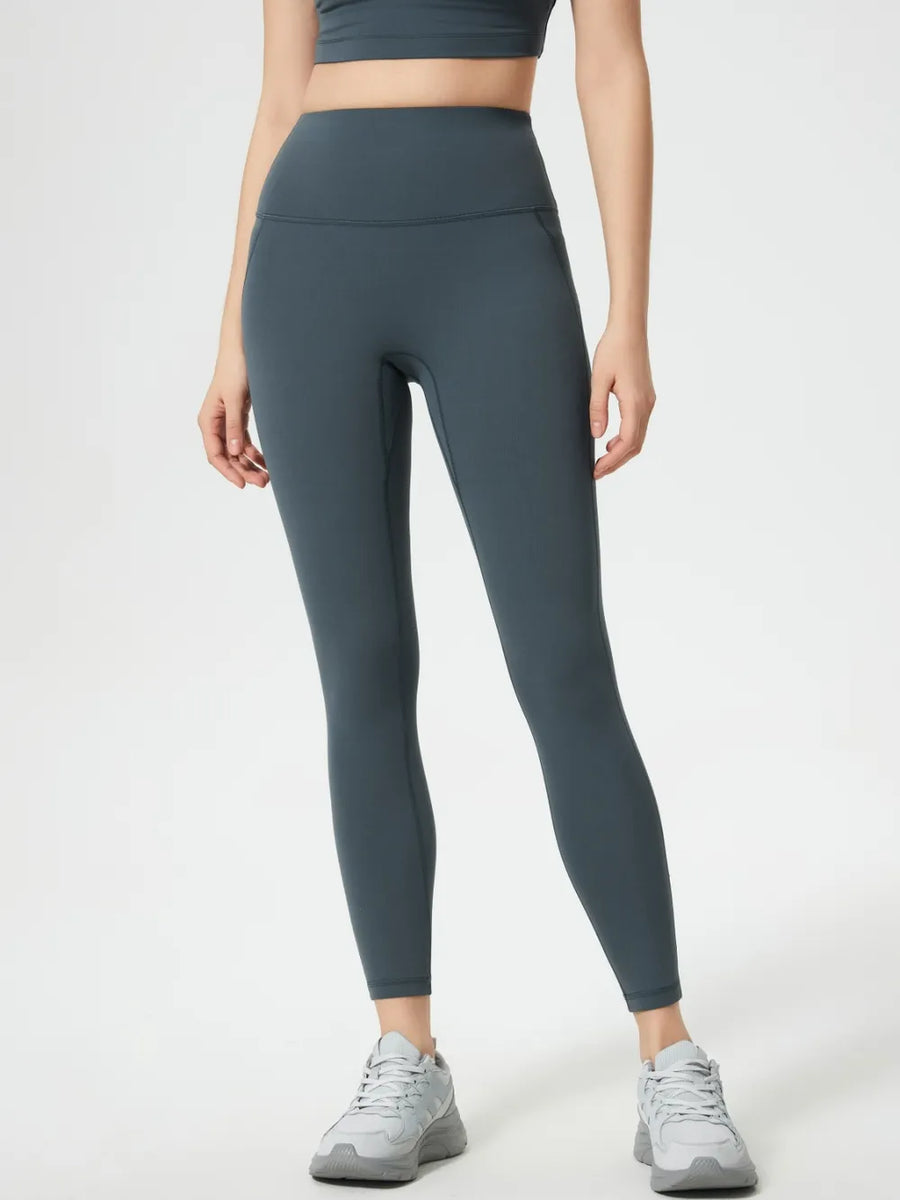 Person wearing dark gray leggings and a black crop top on a white background