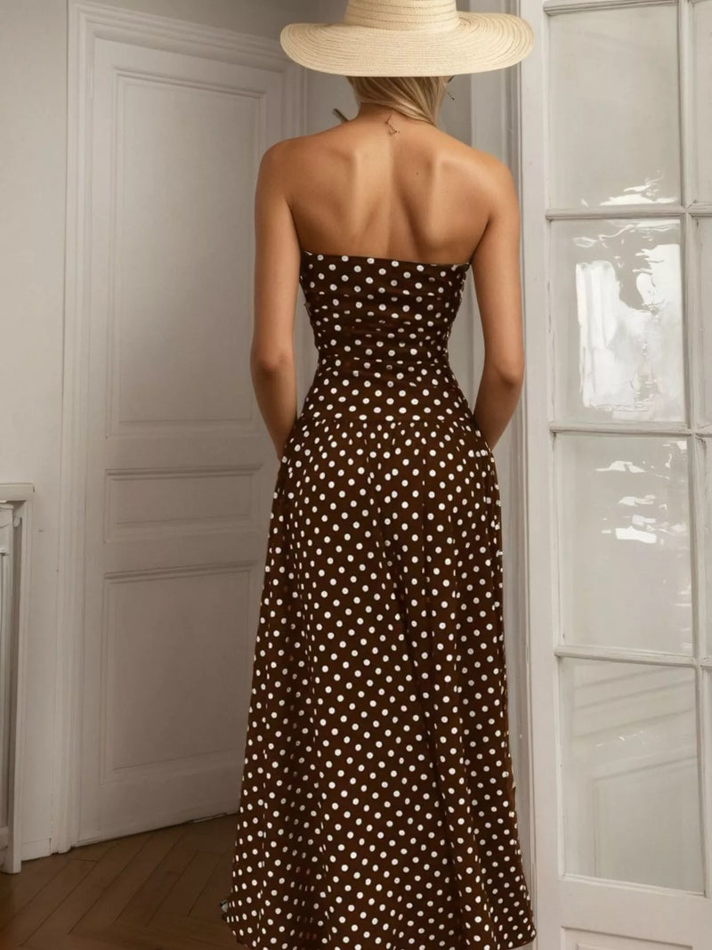 Woman wearing a strapless brown dress with white polka dots and a wide-brimmed hat, standing in a room.