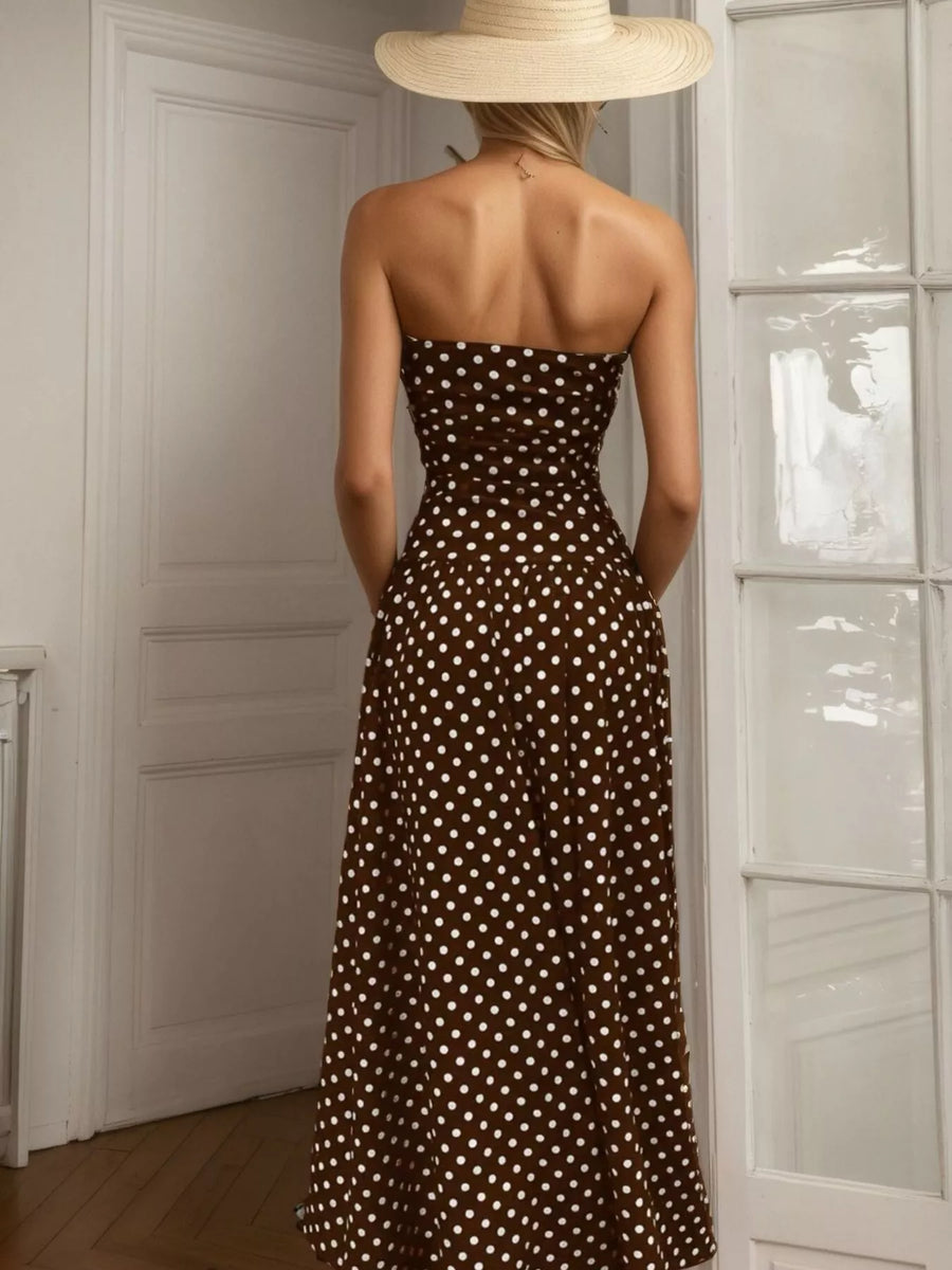 Woman wearing a strapless brown dress with white polka dots and a wide-brimmed hat, standing in a room.