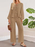 Woman wearing a beige outfit with a plain background and green leaves.