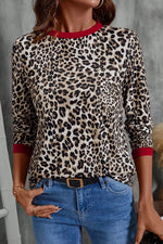 Person wearing a leopard print top with red trim and blue jeans against a gray background