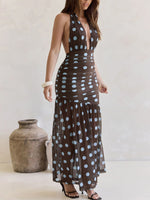 Woman wearing a brown dress with white polka dots standing next to a textured vase.