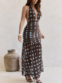 Woman wearing a brown dress with white polka dots standing next to a textured vase.