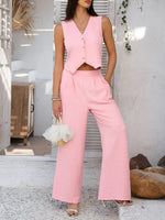 Woman wearing a pink outfit with a vest and wide-leg pants, holding a small white bag.