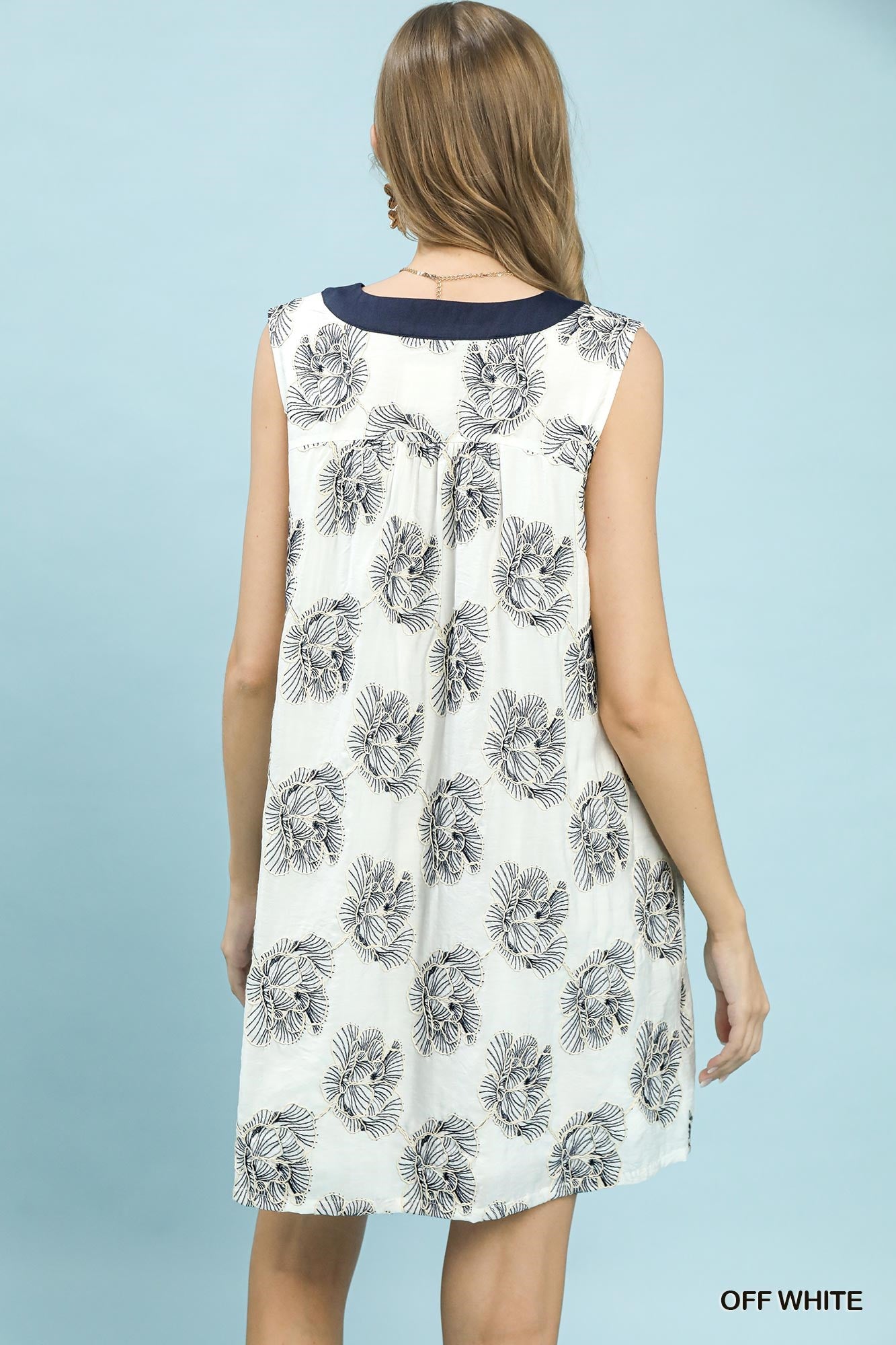 Woman wearing a sleeveless dress with floral pattern on a light blue background