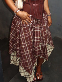 Person wearing a maroon and beige plaid dress with a dark background