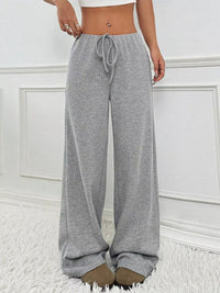 Person wearing gray sweatpants with a white wall background