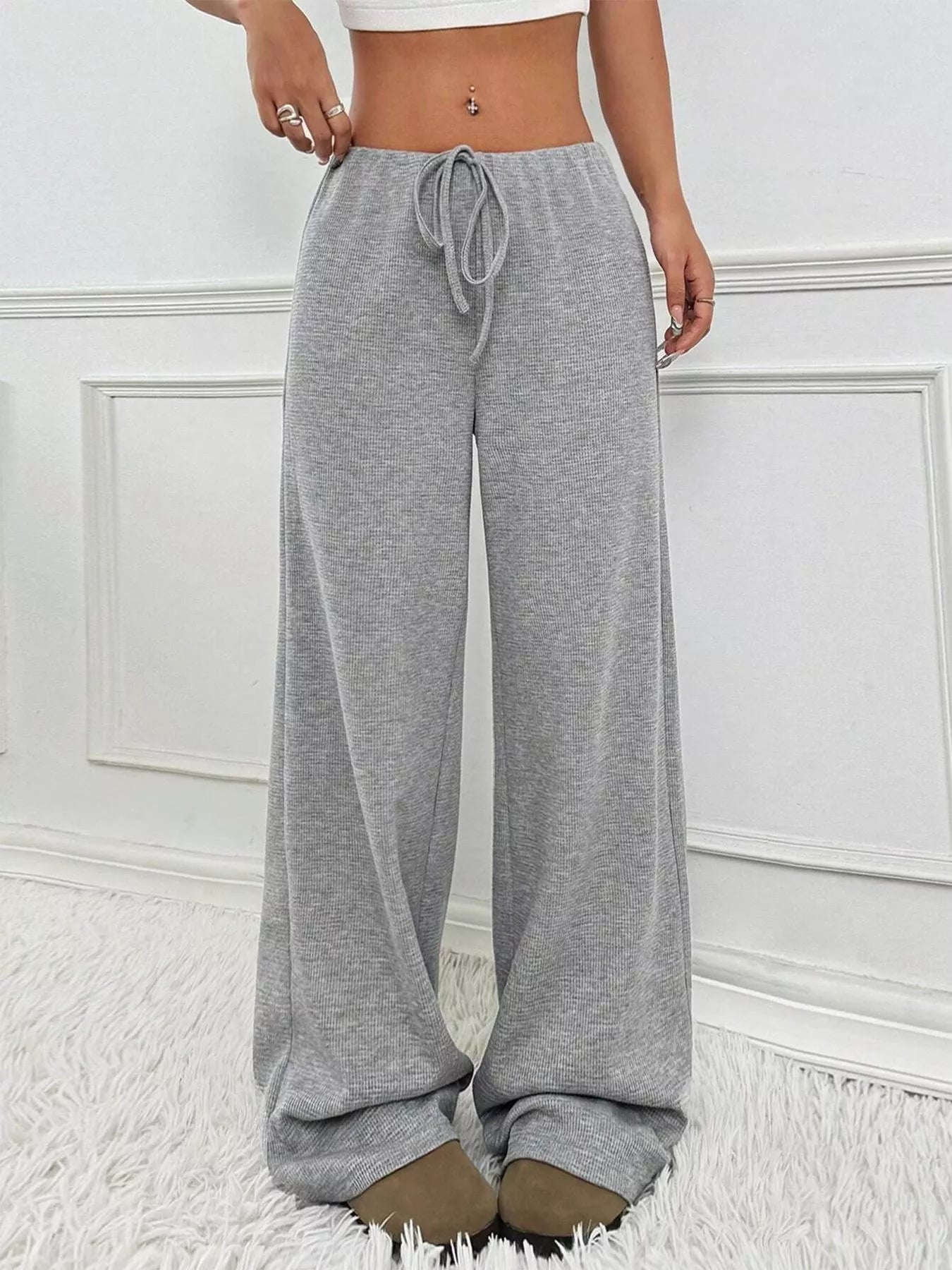 Person wearing gray sweatpants with a white wall background