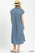 Woman wearing a light denim dress with a straw hat on a white background