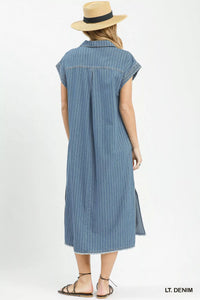 Woman wearing a light denim dress with a straw hat on a white background