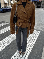 Person wearing a brown suede coat on a city street