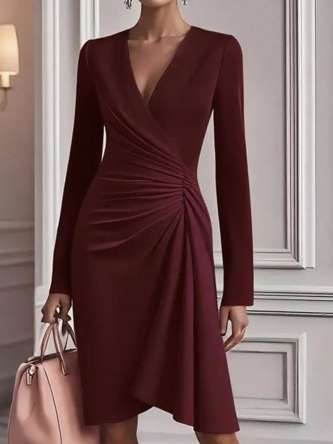 Burgundy dress with long sleeves held by a person against a neutral wall.