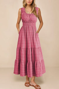 Woman wearing a pink tiered dress against a beige background