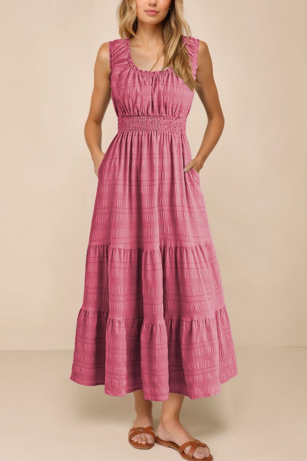 Woman wearing a pink tiered dress against a beige background