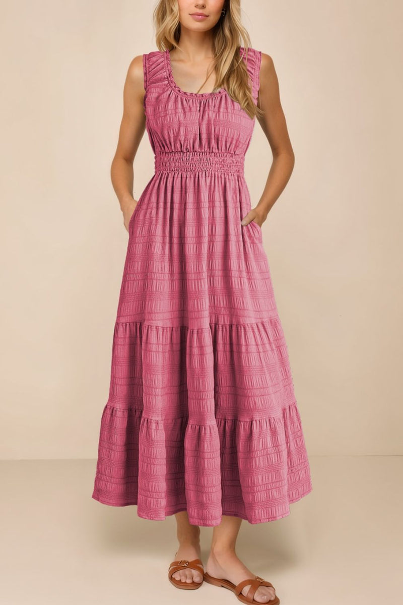 Woman wearing a pink tiered dress against a beige background