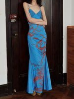 Woman wearing a blue evening gown with red accents in a room.