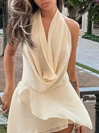 Woman wearing a beige sleeveless dress with a draped neckline in an outdoor setting.
