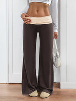 Person wearing brown wide-leg pants and a white top, standing indoors.