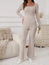 Woman wearing a striped long-sleeve jumpsuit in a cozy room.