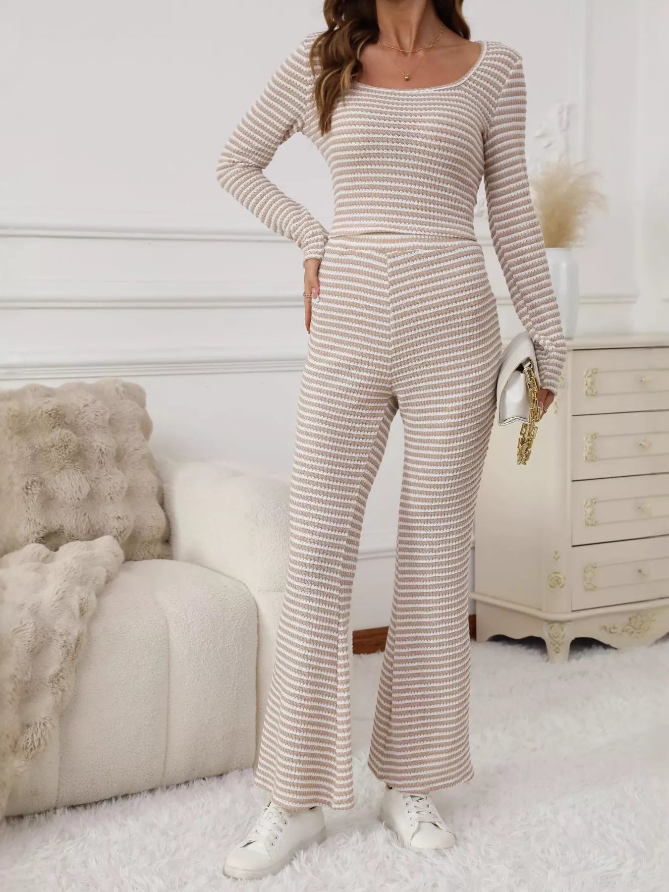 Woman wearing a striped long-sleeve jumpsuit in a cozy room.