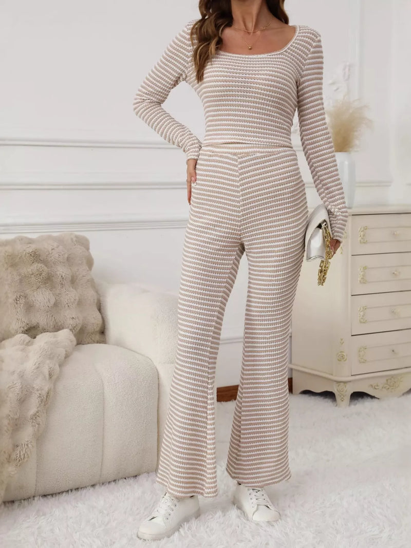 Woman wearing a striped long-sleeve jumpsuit in a cozy room.