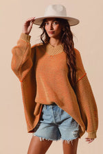 Woman wearing a rust-colored sweater and denim shorts with a beige background