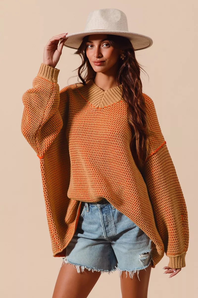 Woman wearing a rust-colored sweater and denim shorts with a beige background